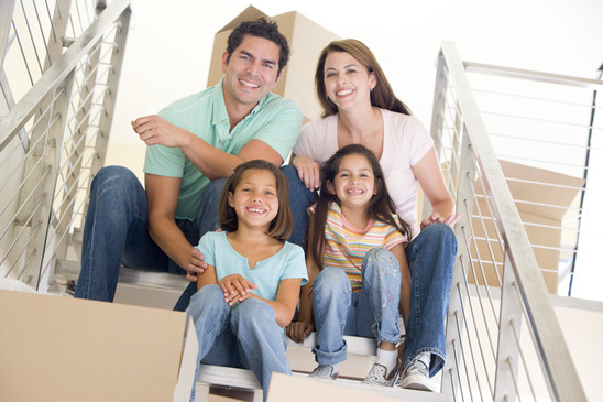 Family sitting on staircase with boxes in new home smiling